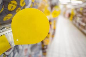 maqueta de etiqueta de descuento amarilla en blanco en los estantes de productos en el supermercado foto