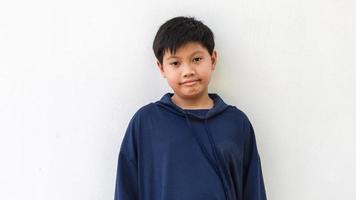 retrato de un lindo niño asiático en una sudadera con capucha posando de pie sonriendo en un feliz aislado sobre fondo blanco.moda de niño asiático lindo foto