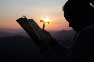 silhouette hand holding cross photo