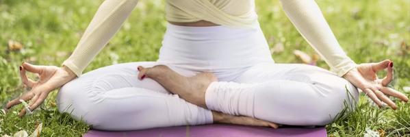 A young beautiful slender girl with long blonde hair does yoga in the summer in nature by the pond in the park. photo