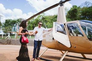 exitosa mujer latina joven inteligente y elegante cerca del helicóptero. concepto de estilo de vida de lujo foto