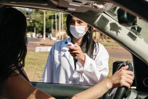 Female Doctor Checking Temperature Using Infrared Thermometer, Tool for detect Coronavirus or Covid-19, the lady in the car. photo