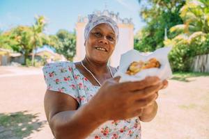 Happy Brazilian woman dressed in traditional Bahian costume, in the historic center of Porto Seguro in the background photo