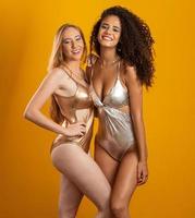Blonde and brunette women having fun portrait against yellow background. A blonde and a brunette. Different types of hair. Racial diversity. Friends. photo
