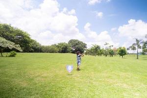 Little boy with afro hair flying a kite on a park photo