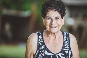 Portrait of smiling beautiful older female farmer. Woman at farm in summer day. Gardening activity. Brazilian elderly woman. photo