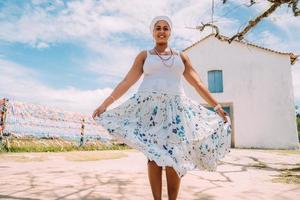 feliz mujer brasileña vestida con traje tradicional bahiano bailando en el centro histórico de porto seguro foto