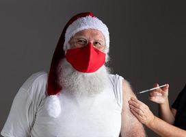 Santa Claus wearing face mask getting vaccinated with injection photo