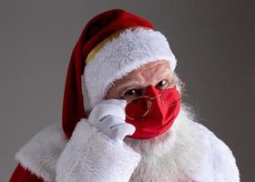 Santa Claus smiles behind red Covid-19 safety face mask. Christmas with social distance. photo