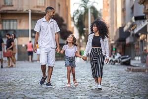 familia tradicional brasileña. padre y madre caminando con su hija. foto