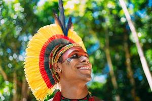 indio de la tribu pataxo con tocado de plumas mirando hacia la derecha. indígenas de brasil con pinturas faciales tradicionales. centrarse en la cara foto