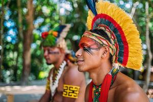 dos indios de la tribu pataxo. indio brasileño del sur de bahia con tocado de plumas, collar y pinturas faciales tradicionales mirando hacia la izquierda foto