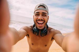 Friendly smiling latin america young man. Man wearing cap and headphones, holding and looking at camera photo