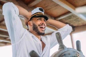 deporte de vela capitán a cargo. hombre latinoamericano con sombrero de capitán de barco preocupado por los piratas foto