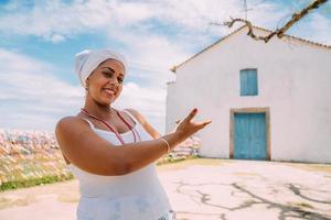 Happy Brazilian woman dressed in traditional Bahian costume, in the historic center of Porto Seguro in the background photo