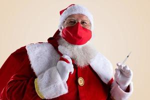 Santa Claus smiles behind red Covid-19 safety face mask. Christmas with social distance. photo