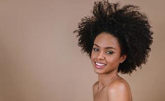 Closeup of a smiling young Latin afro woman. Joy, positive and love. Beautiful african-style hair. Pastel studio background. photo