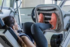 Cute young woman during a leg workout in a gym photo