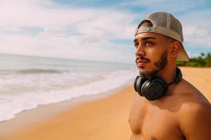 summer holidays, technology and internet concept. latin american man with headset and cap looking to the left photo