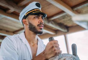deporte de vela capitán a cargo. hombre latinoamericano con sombrero de capitán de barco. foto
