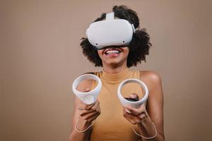 Latin young woman standing with VR goggles and keep joysticks or finger as a gun. photo