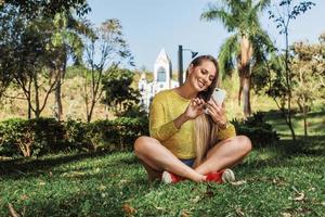 hermosa mujer tomando selfie con su teléfono inteligente en el campo. iglesia en segundo plano. foto