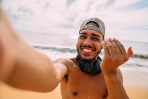 Friendly young Latin American man inviting to come to Brazil, confident and smiling making a gesture with his hand, being positive and friendly photo
