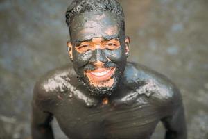 smiling young latin american man doing green clay treatment. focus on face photo