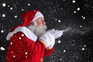 tradiciones navideñas. santa soplando copos de nieve. foto