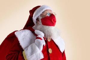 Santa Claus smiles behind red Covid-19 safety face mask. Christmas with social distance. photo