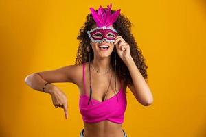 Beautiful woman dressed for carnival night. Smiling woman ready to enjoy the carnival with a colorful mask. Pointing down. photo