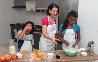 Mother and children preparing lunch together in the kitchen. Messy children. photo