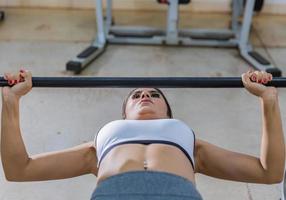 Girl training with bench press in a gym photo