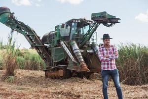 hombre de negocios rural revisando el trabajo. máquina cosechadora de caña de azúcar. granjero. foto