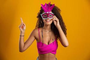 Beautiful woman dressed for carnival night. Smiling woman ready to enjoy the carnival with a colorful mask. Pointing up. photo