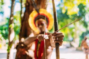 indio de la tribu pataxo usando un arco y una flecha. indio brasileño con tocado de plumas y collar. centrarse en el arco y la flecha foto