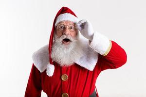 Santa Claus in eyeglasses is looking surprised at camera on white background photo