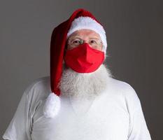 Santa Claus smiles behind red Covid-19 safety face mask. Christmas with social distance. photo