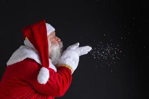 Christmastime traditions. Santa blowing snowflakes. photo