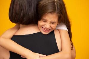 Portrait of a crying little girl who is being held by her mother photo