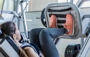 Cute young woman during a leg workout in a gym photo