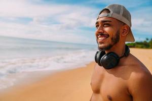 summer holidays, technology and internet concept. smiling latin american man with headset and cap looking to the left photo