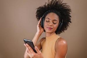 hermosa chica latina usando su teléfono móvil. escuchando música en los auriculares. foto