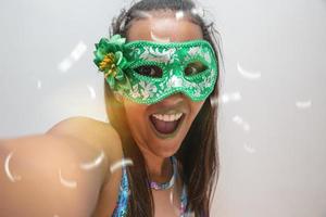 happy young woman with mask and confetti at carnaval party. Brazilian Carnival photo