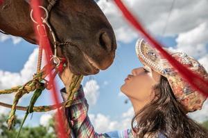 Beautiful brunette girl kissing her horse photo