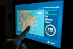 touch screen, close up of a man pointing finger to LCD screen monitor behind passenger seat on the airplane photo