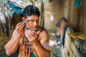 Indian from the Pataxo tribe, using a mirror and doing face painting. photo