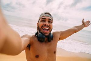 amable joven latinoamericano invitando a venir a brasil, confiado y sonriente haciendo un gesto con la mano, siendo positivo y amigable foto