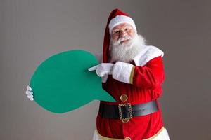 santa claus sosteniendo un globo de texto en blanco. foto