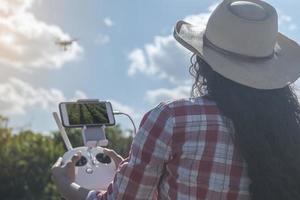 Young woman farmer analyzing a coffee plantation through a drone. Farmer using drone to fly over his coffee plantation. Technology on the farm. photo